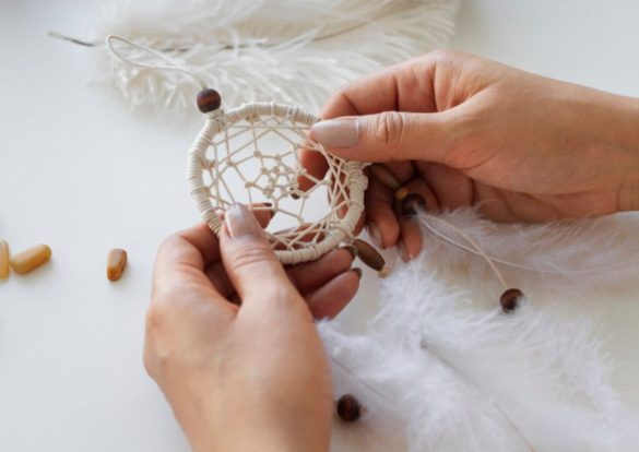 Gros plan sur des mains artisanales assemblant un petit Attrape-Rêves.
