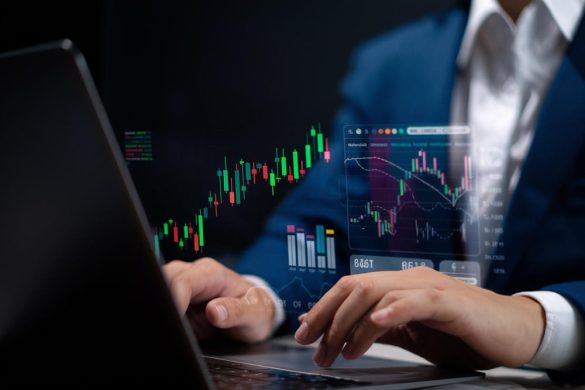 Gros plan des mains d’un homme d'affaires en costume qui analyse des graphiques boursiers en direct et des indicateurs de trading complexes sur son ordinateur portable, avec des projections de données holographiques.