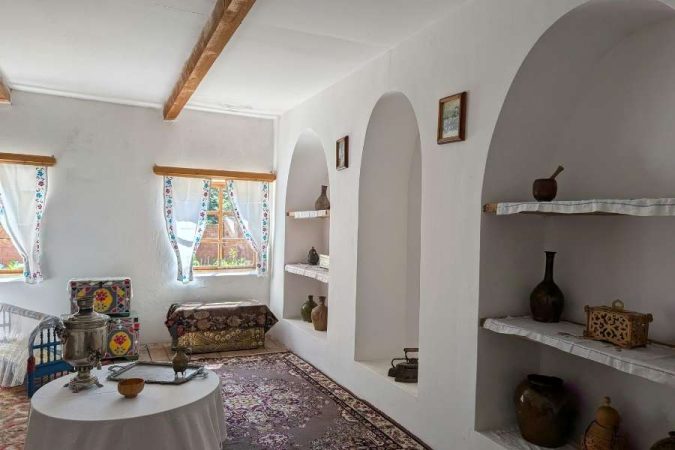 Un intérieur élégant de style traditionnel avec des niches en arche blanches, des objets anciens et un tapis oriental coloré.
