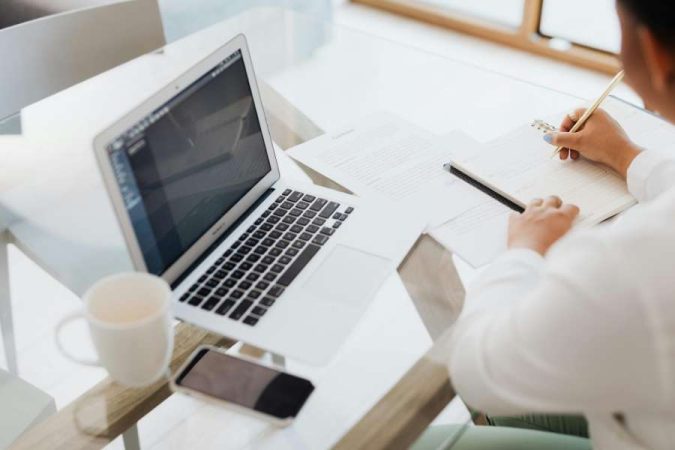 Une personne utilise son MacBook Air pour rédiger un CV en ligne avec l'assistance d'une IA.