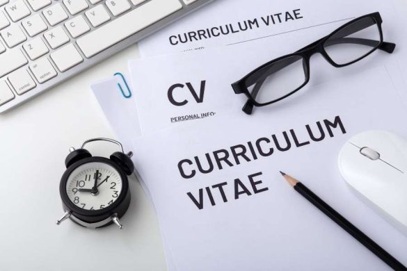 Une vue de dessus d'un bureau avec des documents 'Curriculum Vitae', un réveil, des lunettes et une souris.