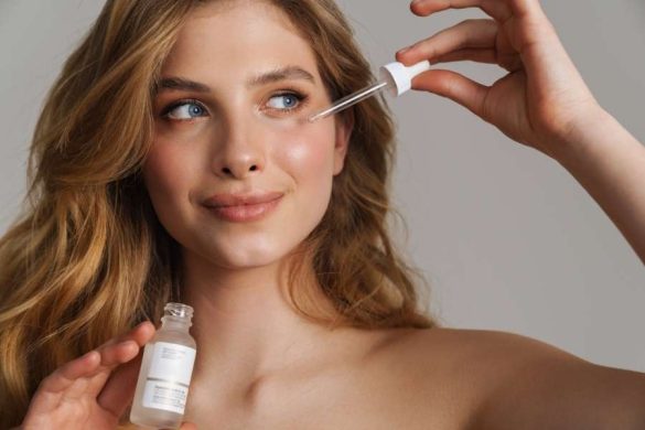 Une femme blonde utilise une pipette pour appliquer un sérum illuminateur sous ses yeux.